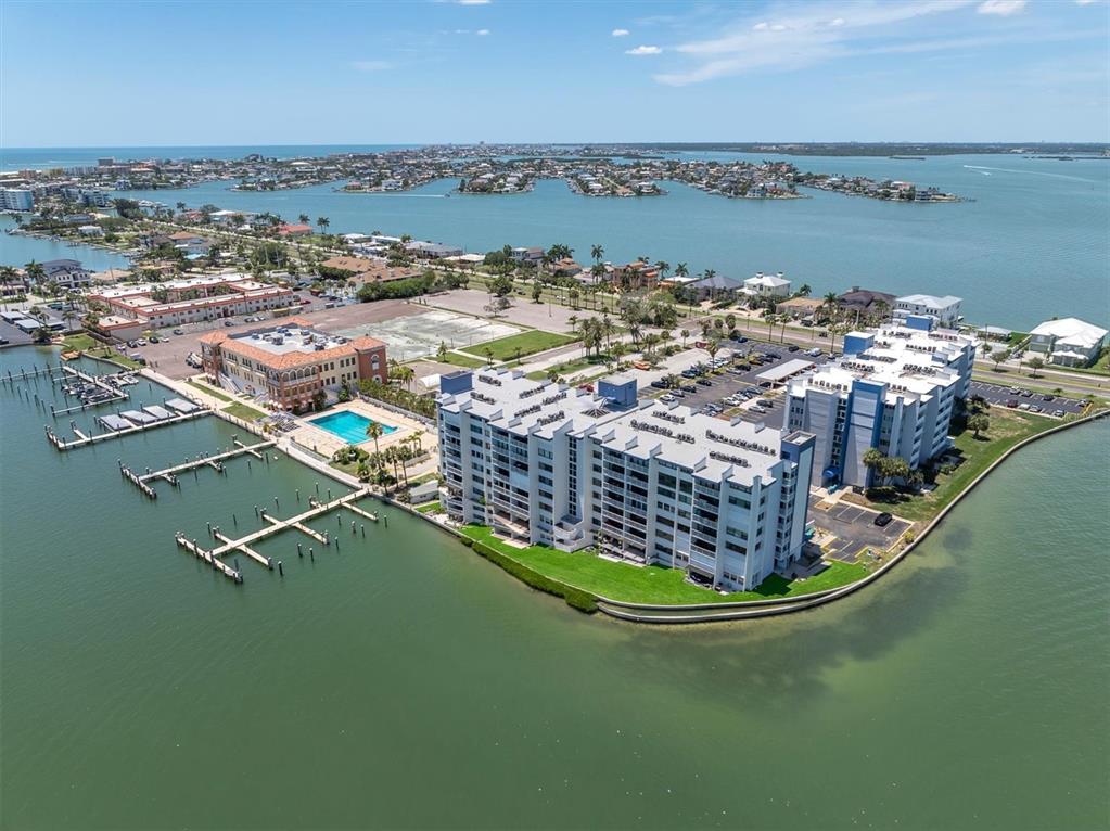An aerial view shows a waterfront condominium complex with a pool and boat docks — 450 TREASURE ISLAND CAUSEWAY UNIT 102, TREASURE ISLAND, FL