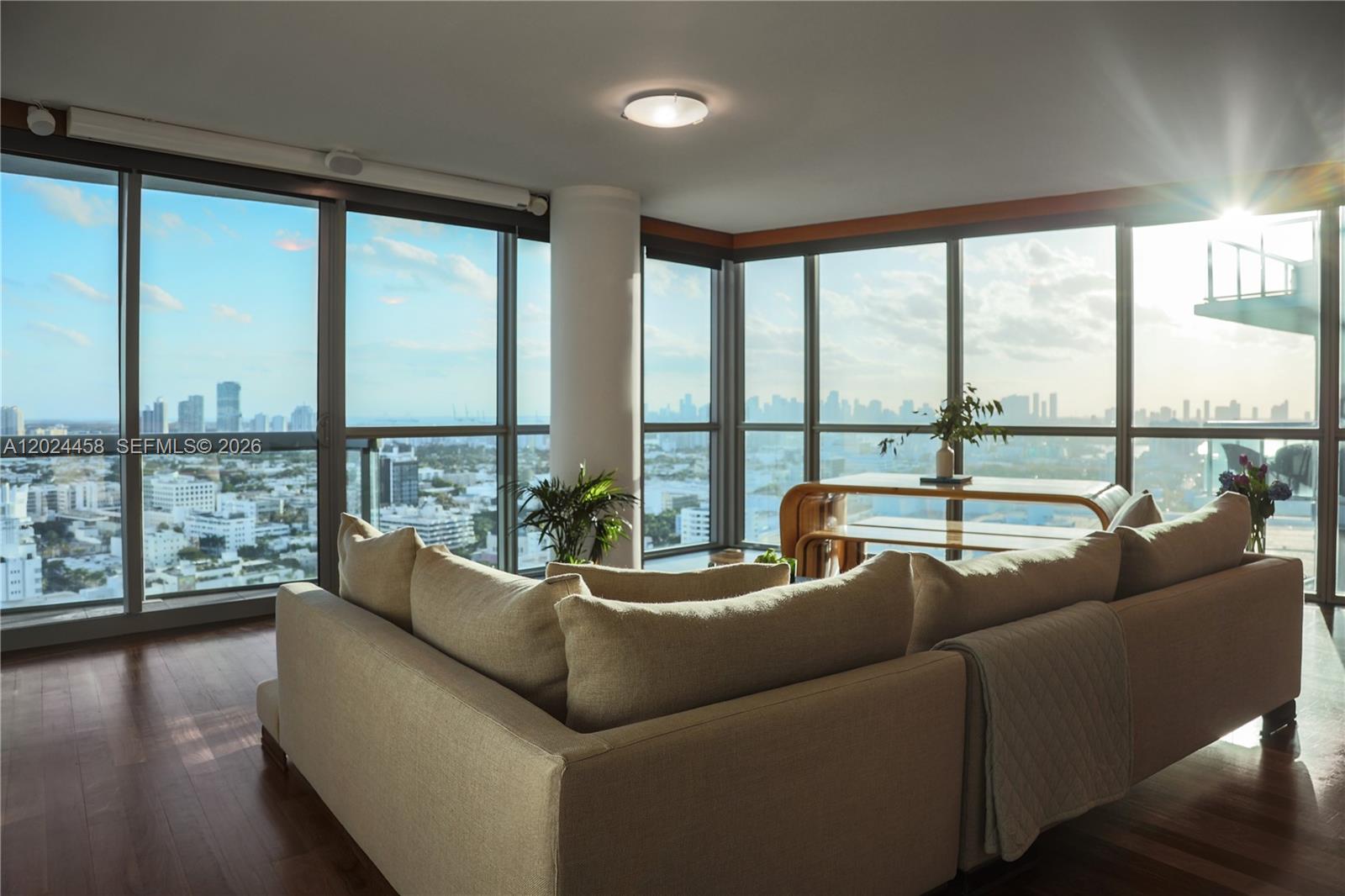 A living room features a large sectional sofa, hardwood floors, and floor-to-ceiling windows with city views — 101 20th St # 3206, Miami Beach FL 33139, MIAMI BEACH, FL