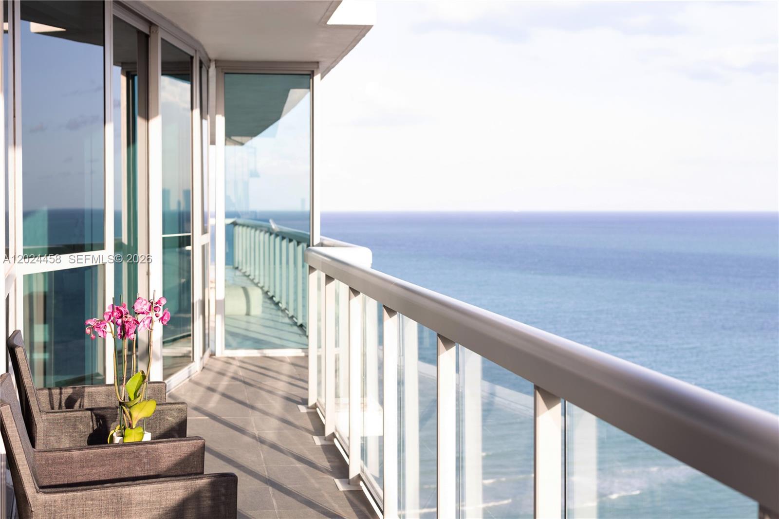 A high-rise balcony features glass railings, dark patio chairs, and an orchid overlooking the ocean — 101 20th St # 3206, Miami Beach FL 33139, MIAMI BEACH, FL