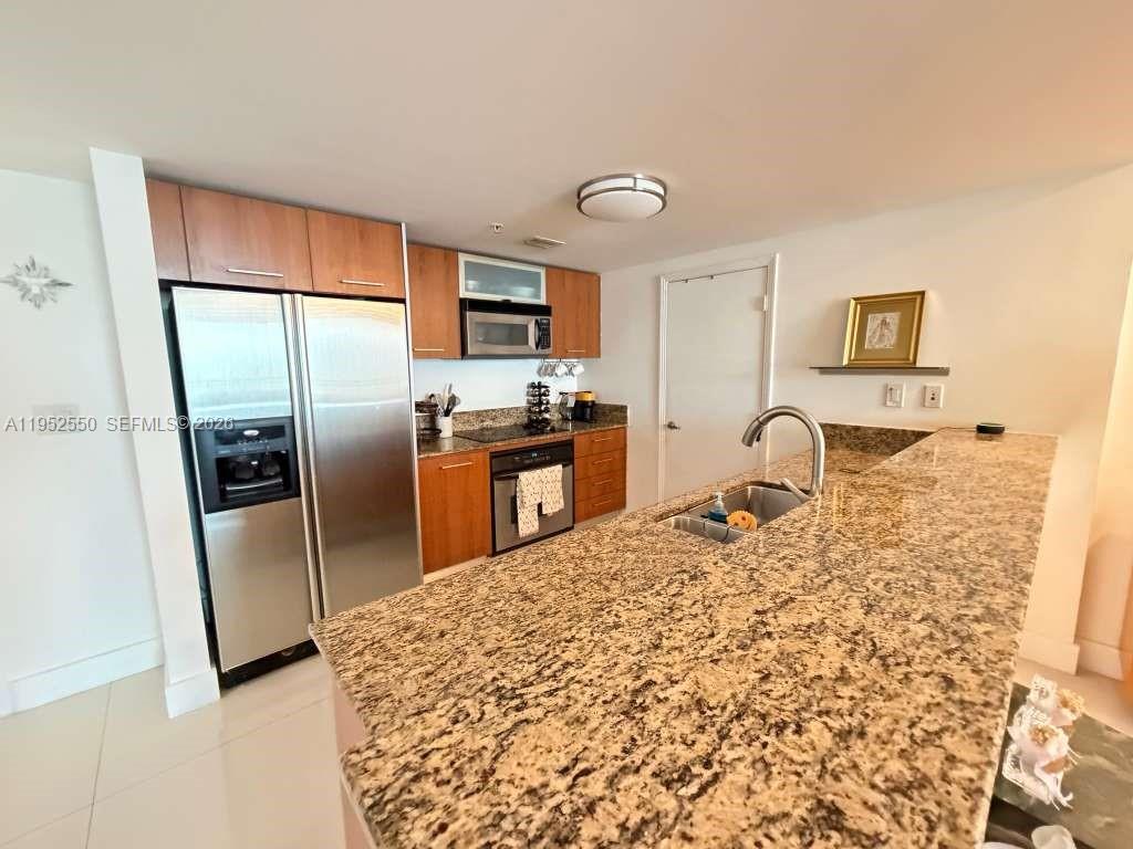 A kitchen features wood cabinets, granite countertops, stainless steel appliances, and a breakfast bar — 9066 SW 73rd Ct # 1105, Miami FL 33156, MIAMI, FL