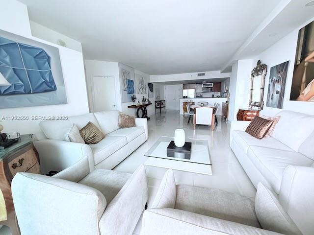 A bright, open-concept living room features white sofas, a glass coffee table, and tiled floors — 9066 SW 73rd Ct # 1105, Miami FL 33156, MIAMI, FL