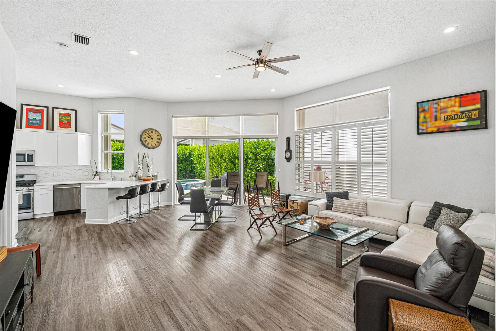 An open-concept living room and kitchen featuring white cabinetry, wood-look flooring, and a sliding door — 4278 NW 65th Road, Boca Raton FL 33496, BOCA RATON, FL