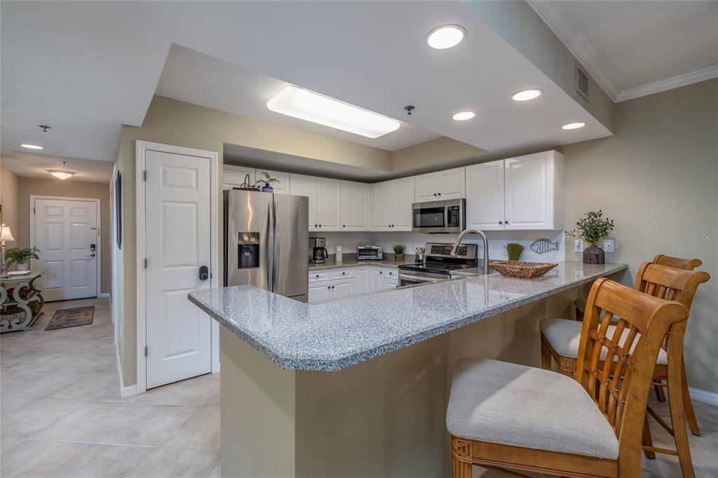 A kitchen features white cabinets, granite countertops, stainless steel appliances, and a breakfast bar — 5300 S ATLANTIC AVENUE UNIT 8-304, NEW SMYRNA BEACH, FL