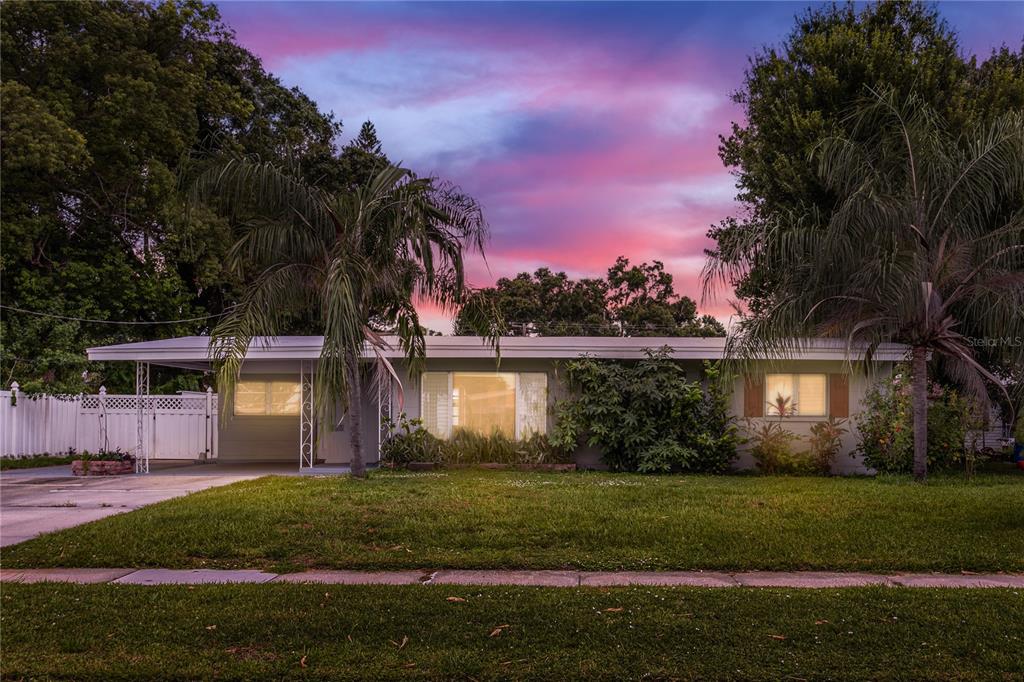 A single-story house with a flat roof, carport, and lawn at sunset — 6518 WALTON WAY, TAMPA, FL