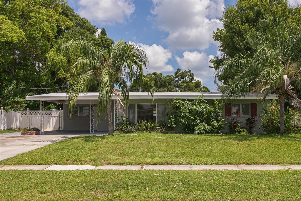 A single-story house with a carport, palm trees, and a front lawn under a blue sky — 6518 WALTON WAY, TAMPA, FL