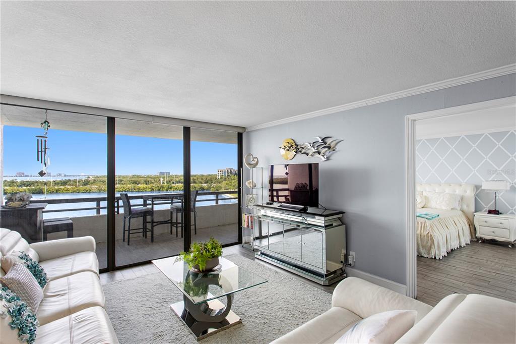 A living room with white sofas, a glass coffee table, and a balcony overlooking water — 5701 MARINER STREET UNIT 504A, TAMPA, FL