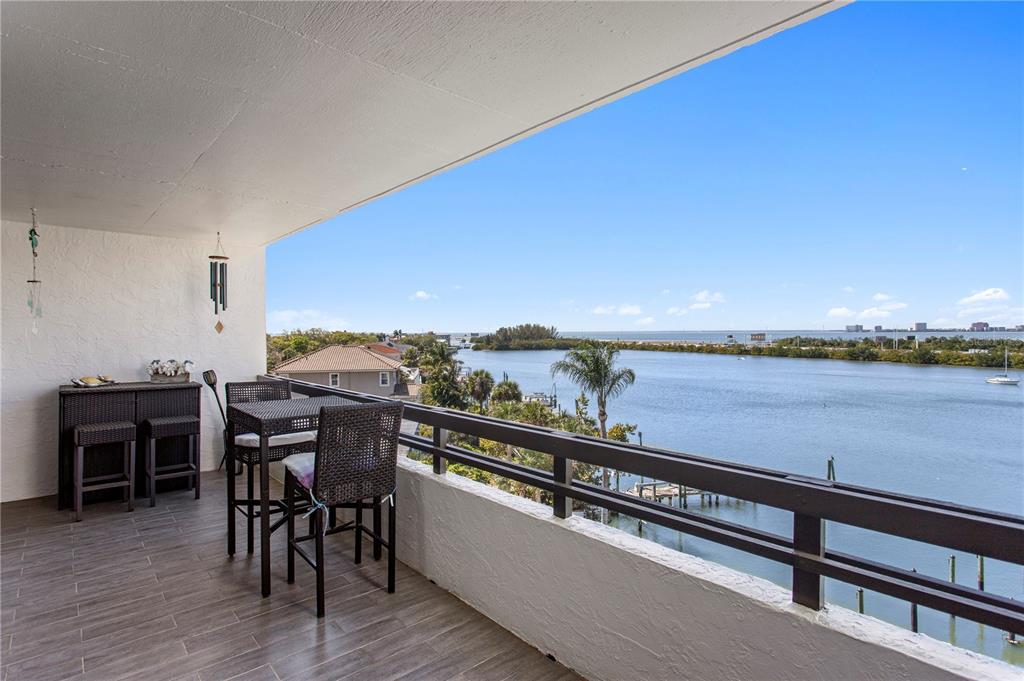 A balcony with outdoor furniture overlooks a body of water and distant coastline — 5701 MARINER STREET UNIT 504A, TAMPA, FL