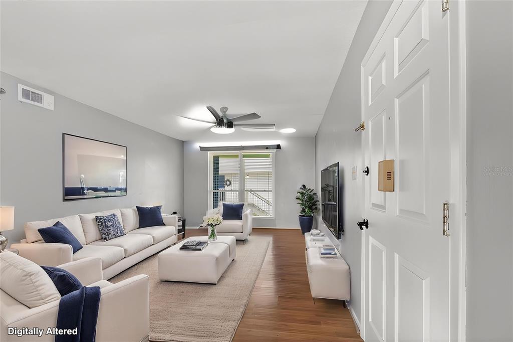 A living room features light gray walls, white furniture, a ceiling fan, and wood flooring — 1935 CONWAY ROAD UNIT L5, ORLANDO, FL