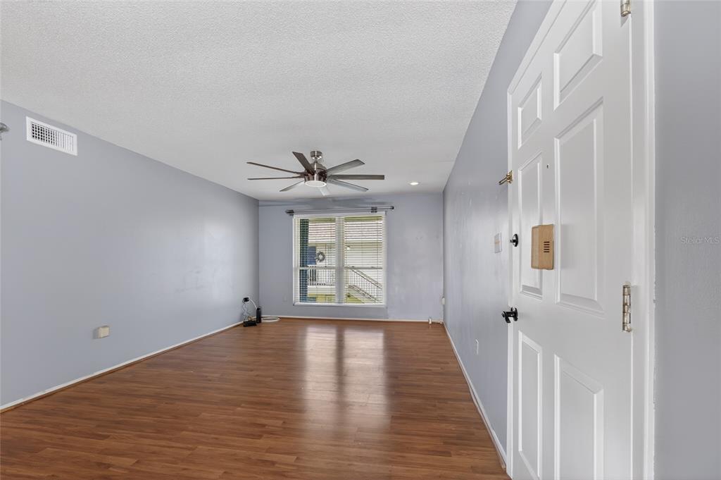 An empty room with light blue walls, wood-look flooring, a ceiling fan, and a window — 1935 CONWAY ROAD UNIT L5, ORLANDO, FL