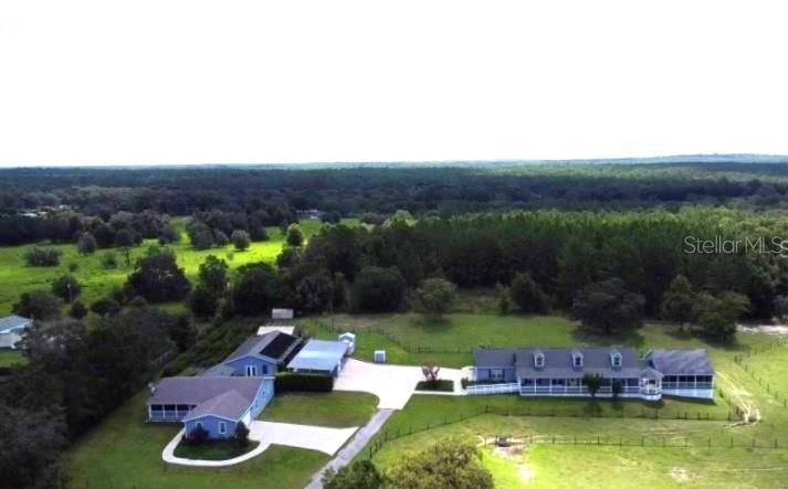 An aerial view shows two blue houses with metal roofs situated on a large grassy lot — 1474 W JACKSON HILL COURT, LECANTO, FL