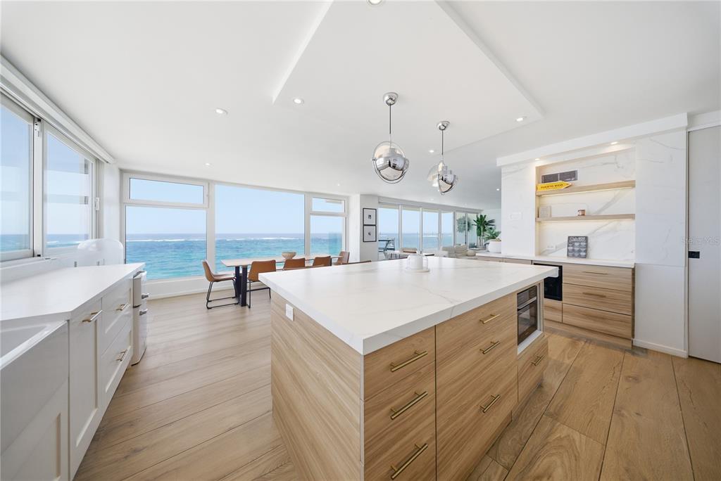 A modern kitchen with a large island, light wood cabinetry, and floor-to-ceiling ocean views — 1 CERVANTES UNIT 9 PH, SAN JUAN, PR