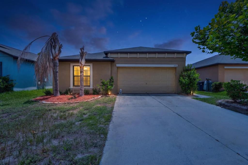A single-story house with a tan stucco exterior, a two-car garage, and a concrete driveway — 14106 COVERT GREEN PLACE, RIVERVIEW, FL
