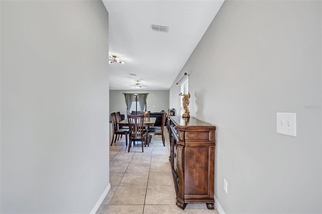 A hallway leads into a dining area with tile floors and a wooden sideboard — 14106 COVERT GREEN PLACE, RIVERVIEW, FL