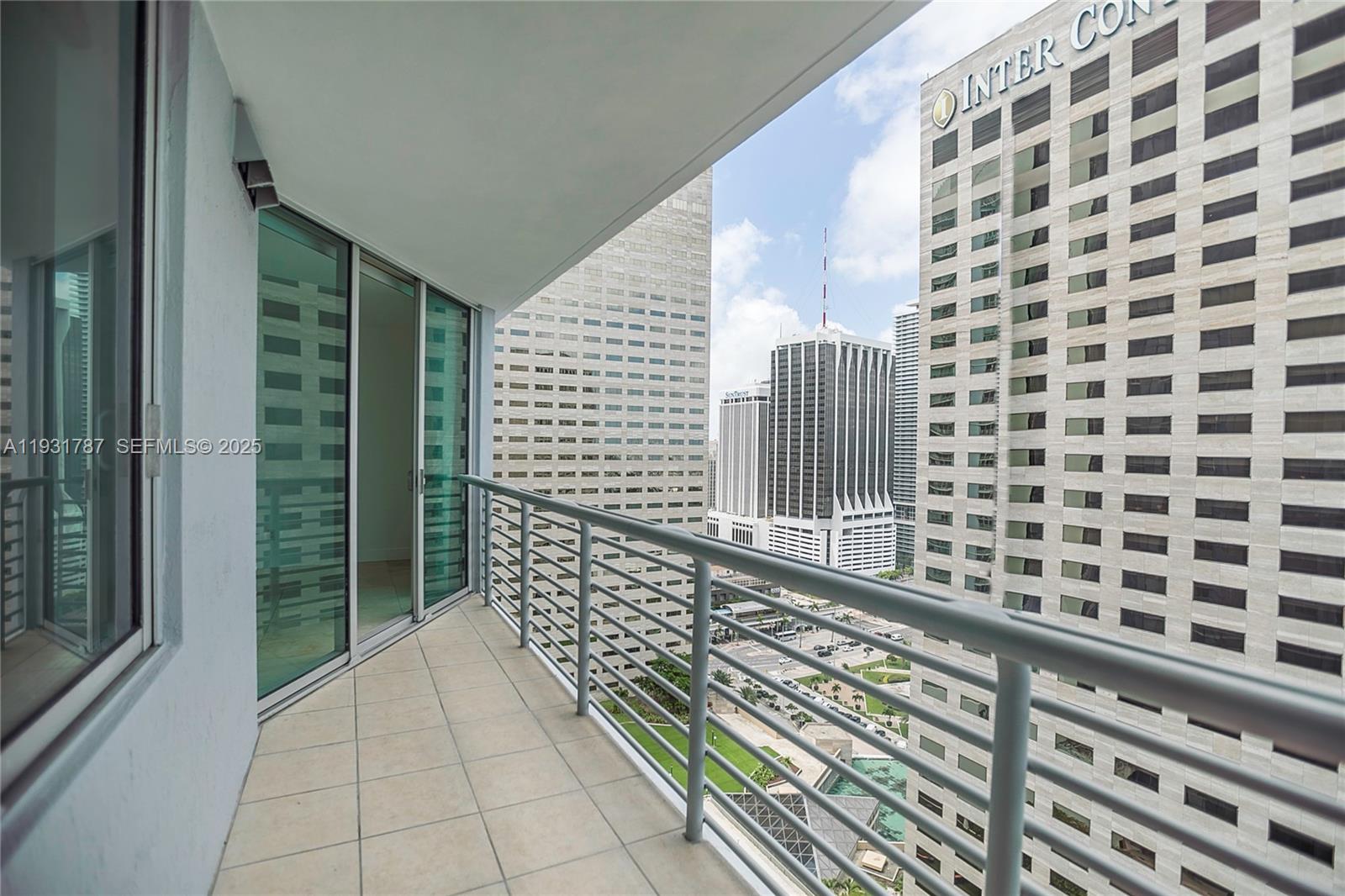 A balcony with tile flooring and a metal railing overlooks a dense urban cityscape — 335 S Biscayne Blvd # 2710, Miami FL 33131, MIAMI, FL