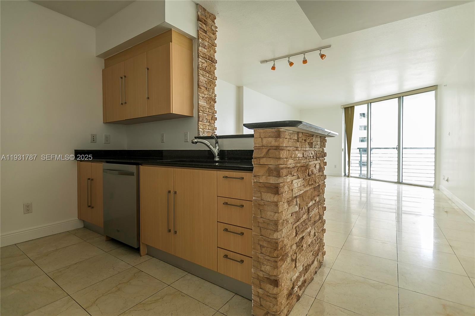 A kitchen features light wood cabinets, black countertops, and a stone-accented breakfast bar — 335 S Biscayne Blvd # 2710, Miami FL 33131, MIAMI, FL