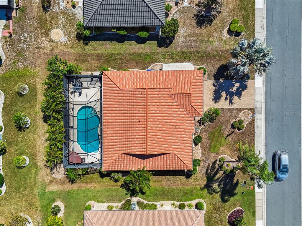 An aerial view shows a house with a red tile roof and a screened-in pool — 706 PLUMBROOK ROAD, SUN CITY CENTER, FL