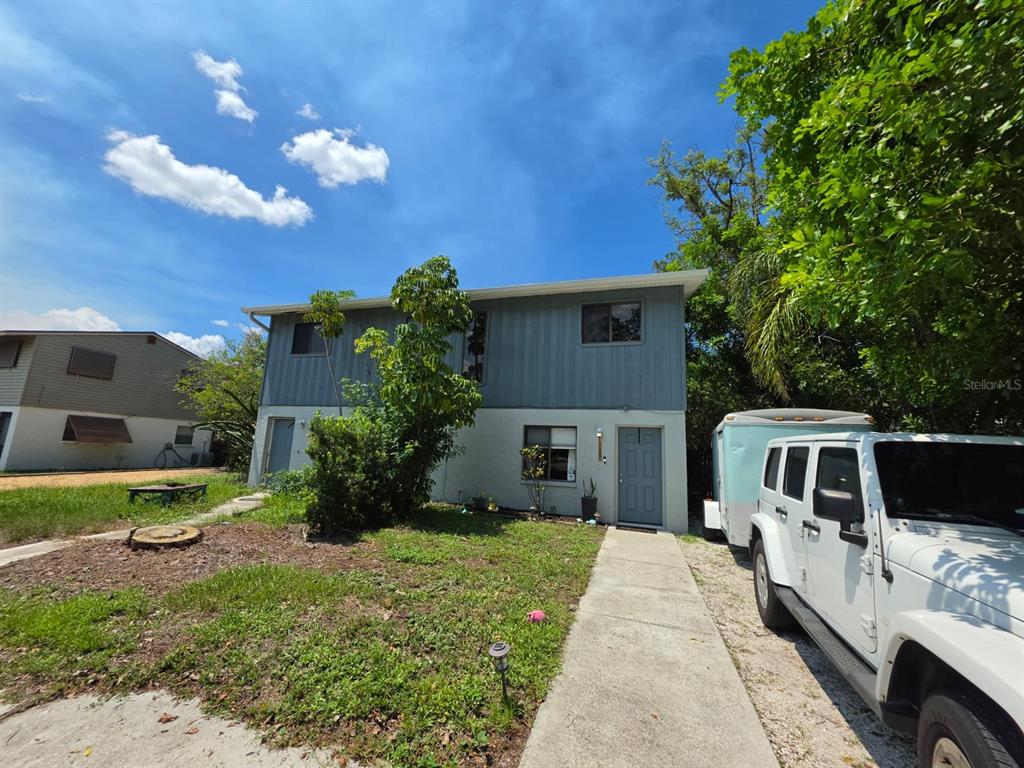 A two-story house with gray vertical siding, a white lower level, and a concrete walkway — 7087 BRENTFORD ROAD, SARASOTA, FL