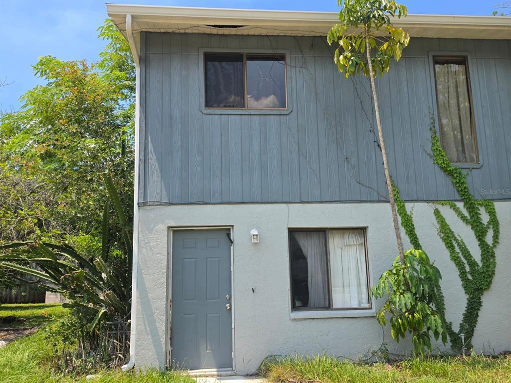 A two-story building exterior features blue vertical siding on top and light gray stucco below — 7087 BRENTFORD ROAD, SARASOTA, FL