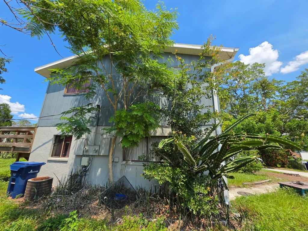 The exterior of a two-story house features gray siding, a large tree, and a cactus plant — 7087 BRENTFORD ROAD, SARASOTA, FL