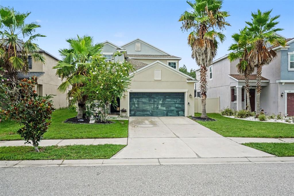 A two-story suburban house with a concrete driveway, a garage, and palm trees in front — 1561 TALLULAH TERRACE, WESLEY CHAPEL, FL