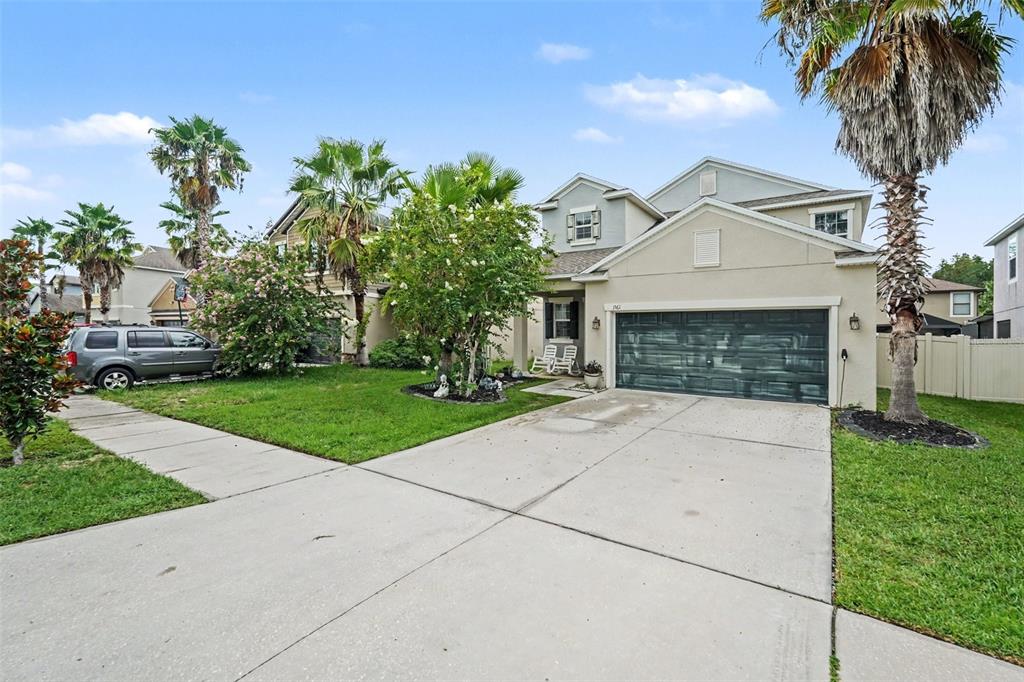 A two-story suburban house features a concrete driveway, a two-car garage, and several palm trees — 1561 TALLULAH TERRACE, WESLEY CHAPEL, FL