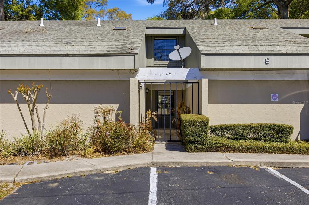 The exterior of a single-story residential unit features a gated entryway and a satellite dish — 7200 SW 8TH AVENUE UNIT S119, GAINESVILLE, FL