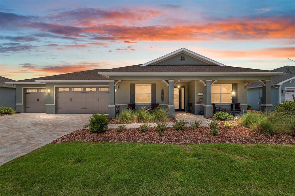 A single-story house with a gray stucco exterior, a paved driveway, and a covered porch — 9577 SW 82ND STREET ROAD, OCALA, FL