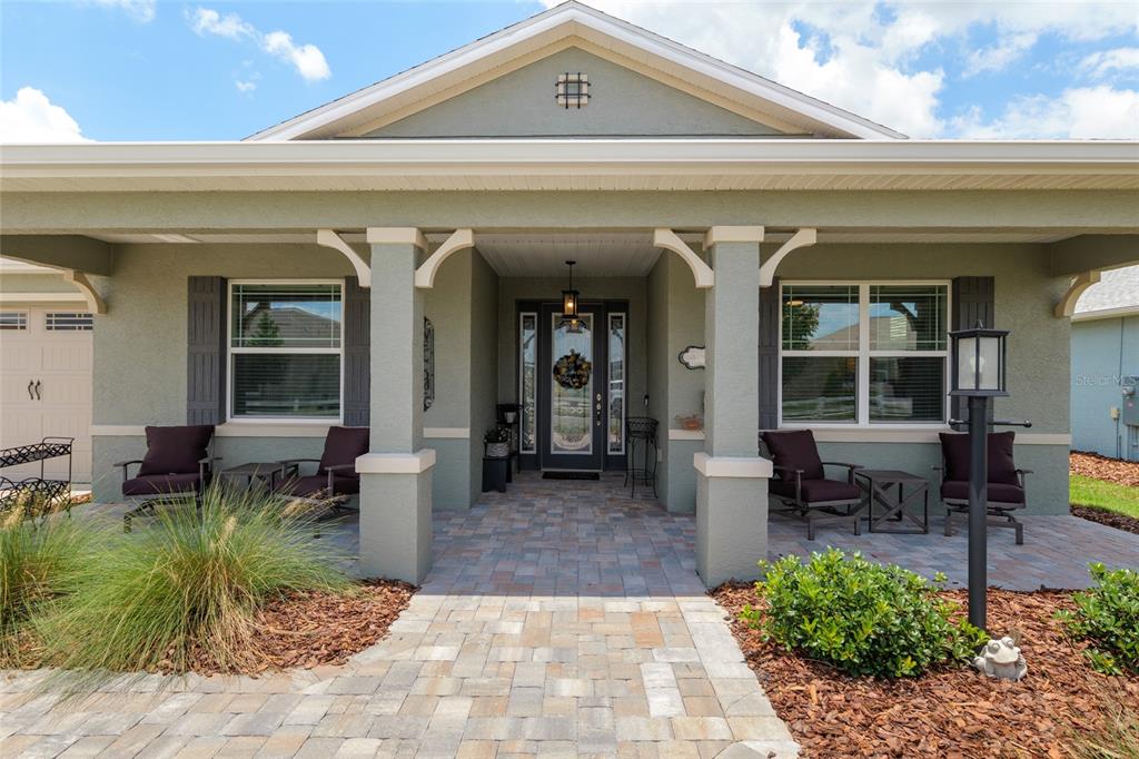 A front porch with a paver walkway, two columns, and four chairs facing the entrance — 9577 SW 82ND STREET ROAD, OCALA, FL
