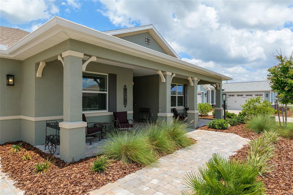 A light green house with a covered porch, stone walkway, and landscaped front yard — 9577 SW 82ND STREET ROAD, OCALA, FL