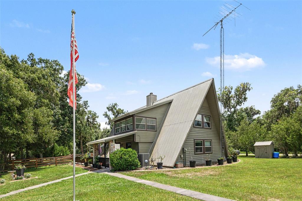 An A-frame house with a metal roof, a tall antenna, and a flagpole in the yard — 11165 E OWNBEY COURT, FLORAL CITY, FL