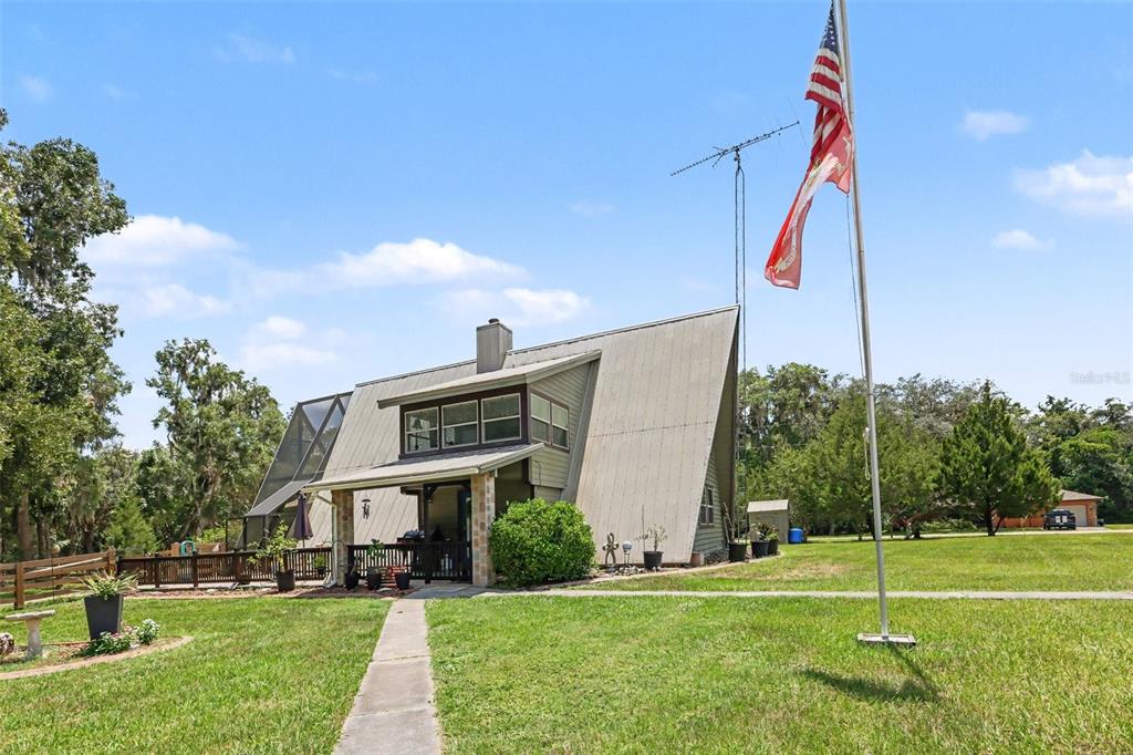 An A-frame house with a metal roof and a flag pole stands on a lawn — 11165 E OWNBEY COURT, FLORAL CITY, FL