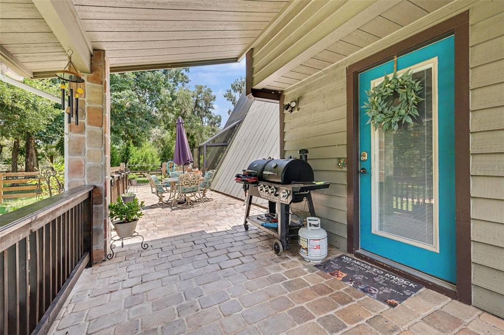 A covered brick patio features a grill, outdoor dining set, and a bright blue door — 11165 E OWNBEY COURT, FLORAL CITY, FL