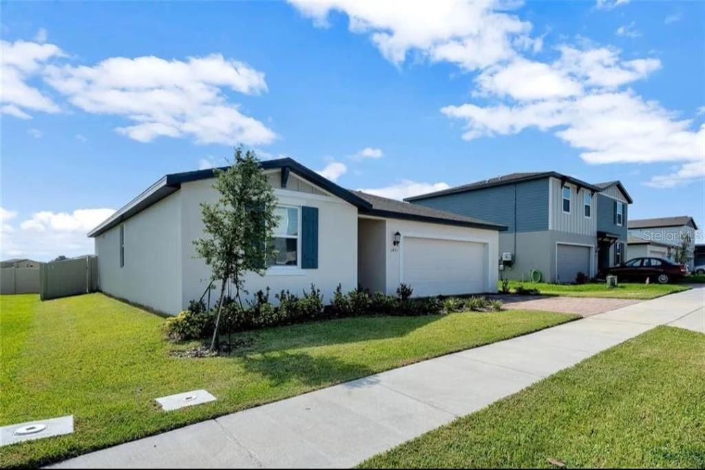 A single-story house with a white exterior, blue shutters, and an attached two-car garage — 1431 SAGUARO STREET, DAVENPORT, FL