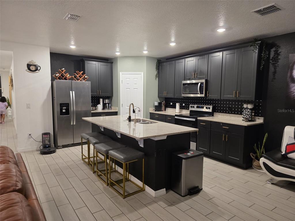 A kitchen features dark cabinetry, a central island with bar seating, and light-colored countertops — 1431 SAGUARO STREET, DAVENPORT, FL
