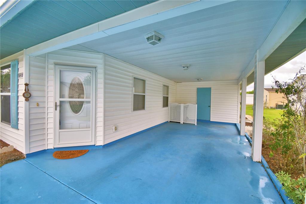 A covered carport with a blue painted concrete floor and white siding exterior — 1690 COLONNADES CIRCLE N, LAKELAND, FL