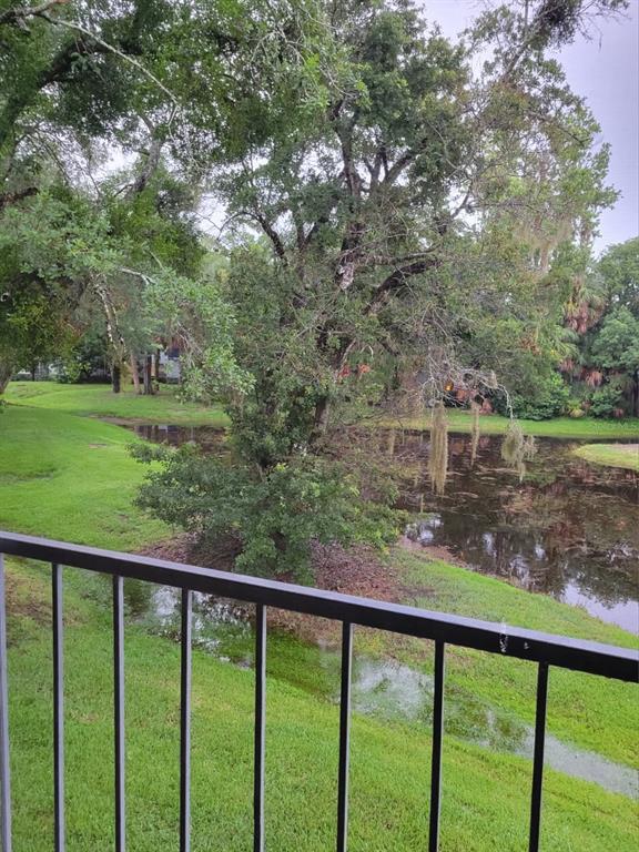 A view from a balcony overlooking a grassy lawn, a small pond, and mature trees — 1808 NORTHLAKE DRIVE UNIT 1808, SANFORD, FL