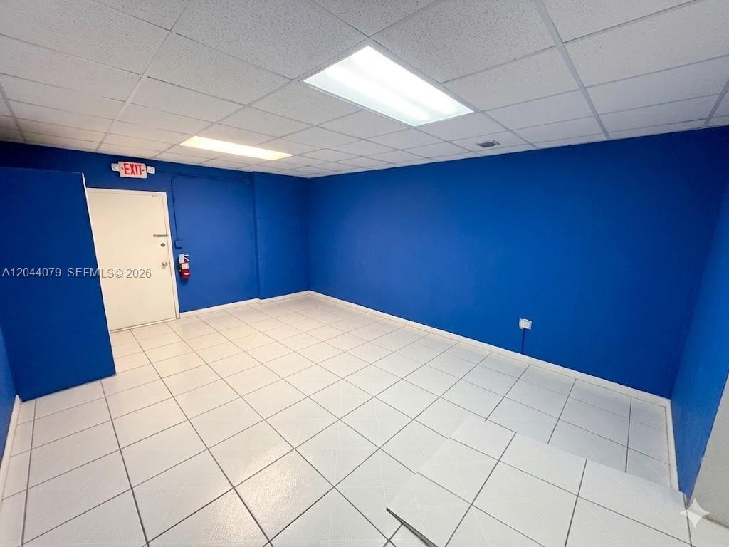 An empty room features blue walls, white tiled flooring, and a drop ceiling with lights — 3130 NW 7th St # 3132, Miami FL 33125, MIAMI, FL