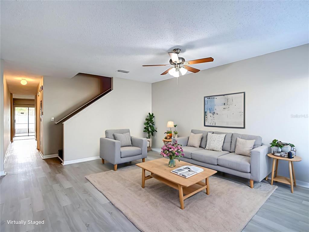 A living room features light gray flooring, a sofa, an armchair, and a staircase — 2245 FLUORSHIRE DRIVE, BRANDON, FL