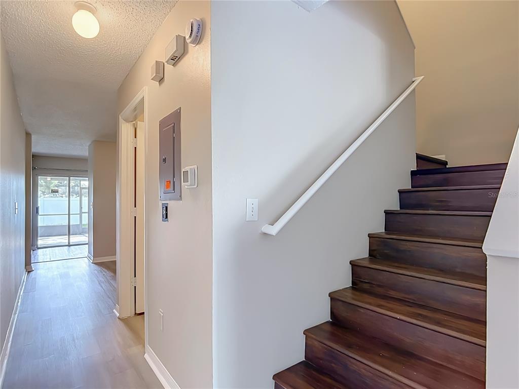 A hallway with light wood flooring leads to a sliding glass door near a staircase — 2245 FLUORSHIRE DRIVE, BRANDON, FL