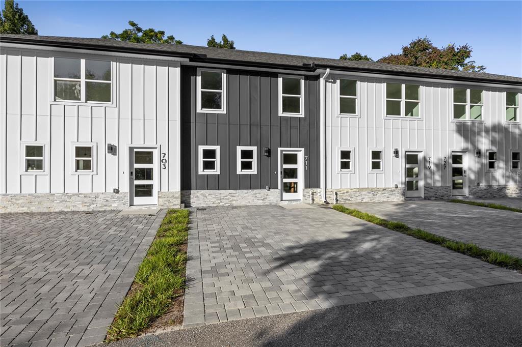 A row of modern townhomes features white and dark gray vertical siding with stone accents — 711 CLEMSON DRIVE, ALTAMONTE SPRINGS, FL