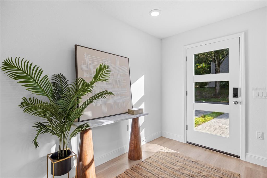 A bright entryway features a white door, a marble-topped console table, and a potted plant — 711 CLEMSON DRIVE, ALTAMONTE SPRINGS, FL