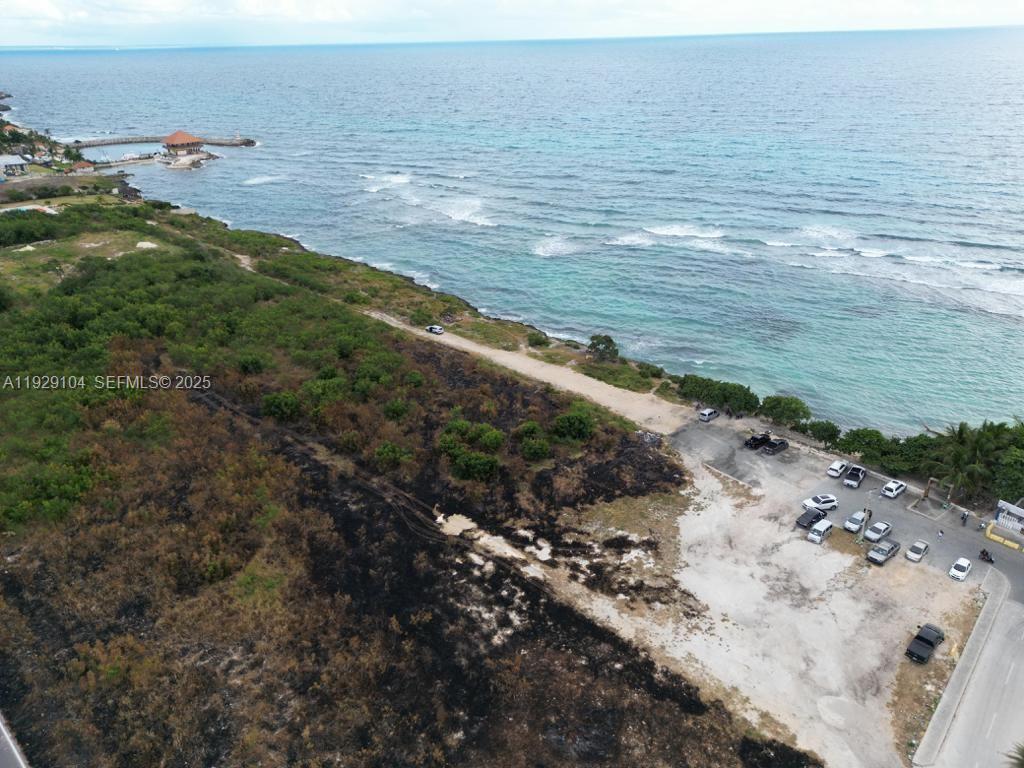 An aerial view shows a coastal lot with a parking area, vegetation, and oceanfront — Villa Caleta, La Romana, Dominican Republic, DR, DR