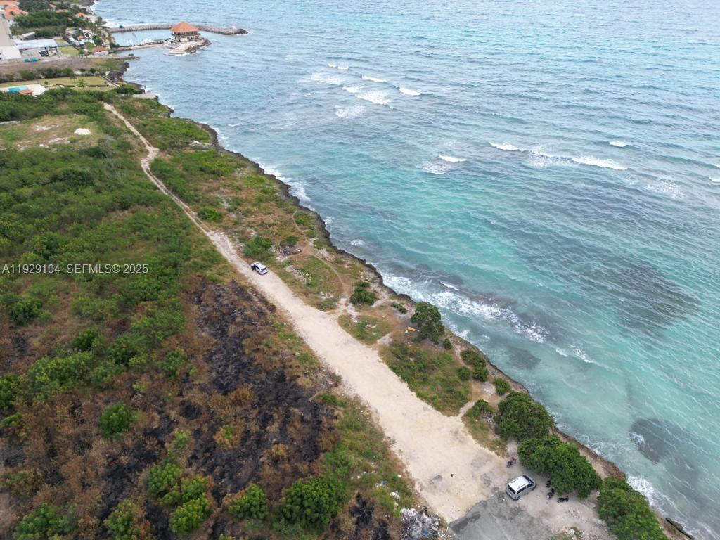 An aerial view shows a dirt road running along a rocky coastline with turquoise water — Villa Caleta, La Romana, Dominican Republic, DR, DR