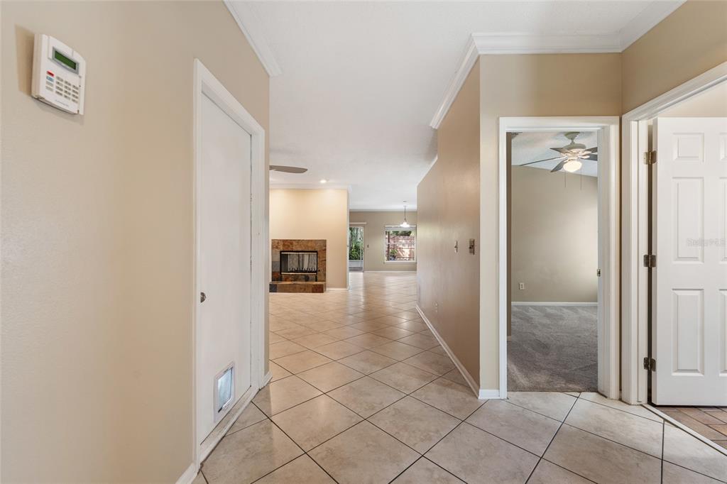 A tiled hallway leads to a living area with a fireplace and a carpeted room — 7909 WALDORF COURT, ORLANDO, FL