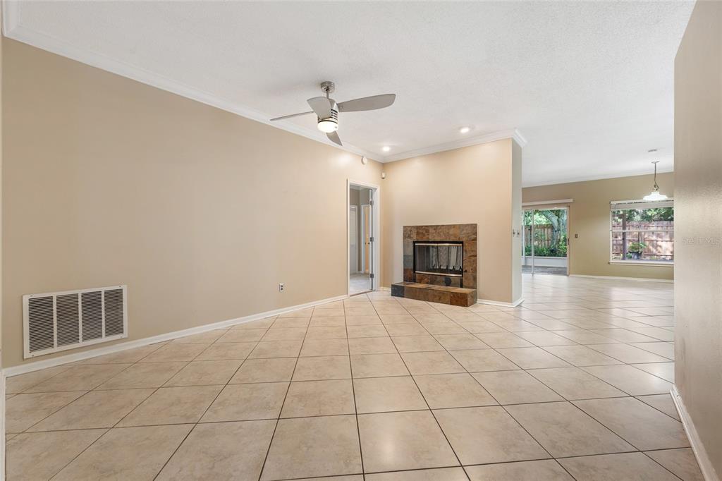 A living room with beige walls, tile flooring, a ceiling fan, and a stone fireplace — 7909 WALDORF COURT, ORLANDO, FL