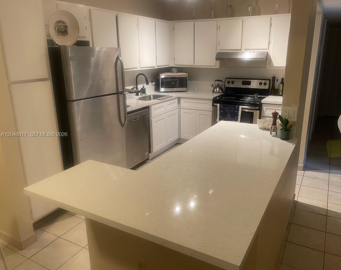 A kitchen features white cabinets, stainless steel appliances, and a large quartz-topped island — 9002 SW 137 ST # 27, Miami FL 33176, MIAMI, FL