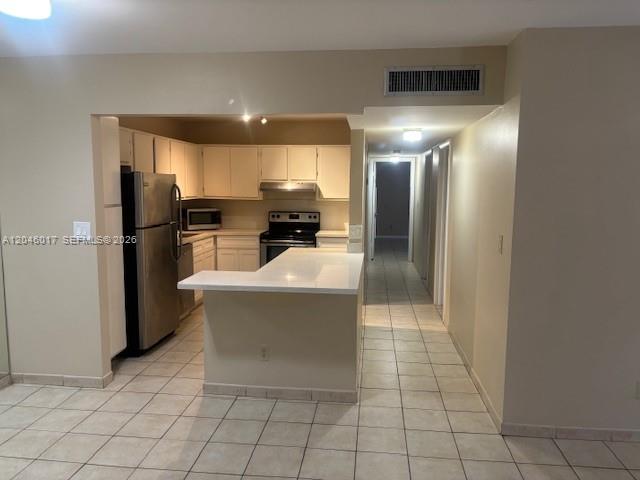 A kitchen features white cabinets, stainless steel appliances, and a white peninsula countertop — 9002 SW 137 ST # 27, Miami FL 33176, MIAMI, FL