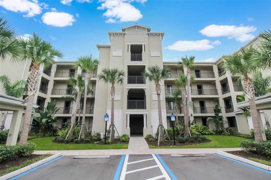 A multi-story apartment building exterior with palm trees and a paved parking lot in front — 17810 GAWTHROP DRIVE UNIT 207, BRADENTON, FL