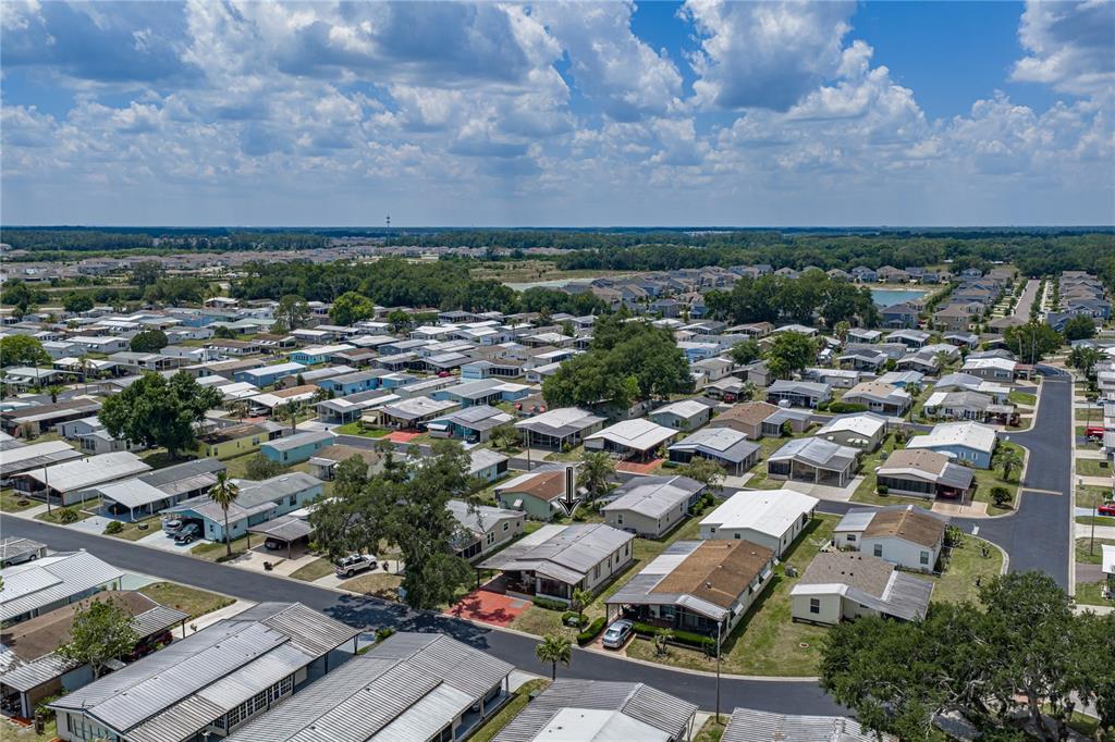 An aerial view shows a residential neighborhood with many manufactured homes and paved streets — 3201 HIDDEN LAKE DRIVE, WESLEY CHAPEL, FL