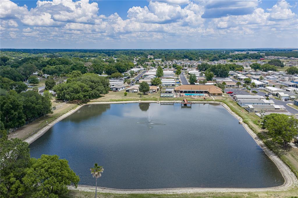 An aerial view shows a large pond with a fountain next to a residential community — 3201 HIDDEN LAKE DRIVE, WESLEY CHAPEL, FL